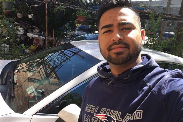 Kaymiul Uddin, a Lyft driver in front of his car.